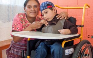 Angel in his new wheelchair and his mother, Eusebia, next to him smiling at the camera.