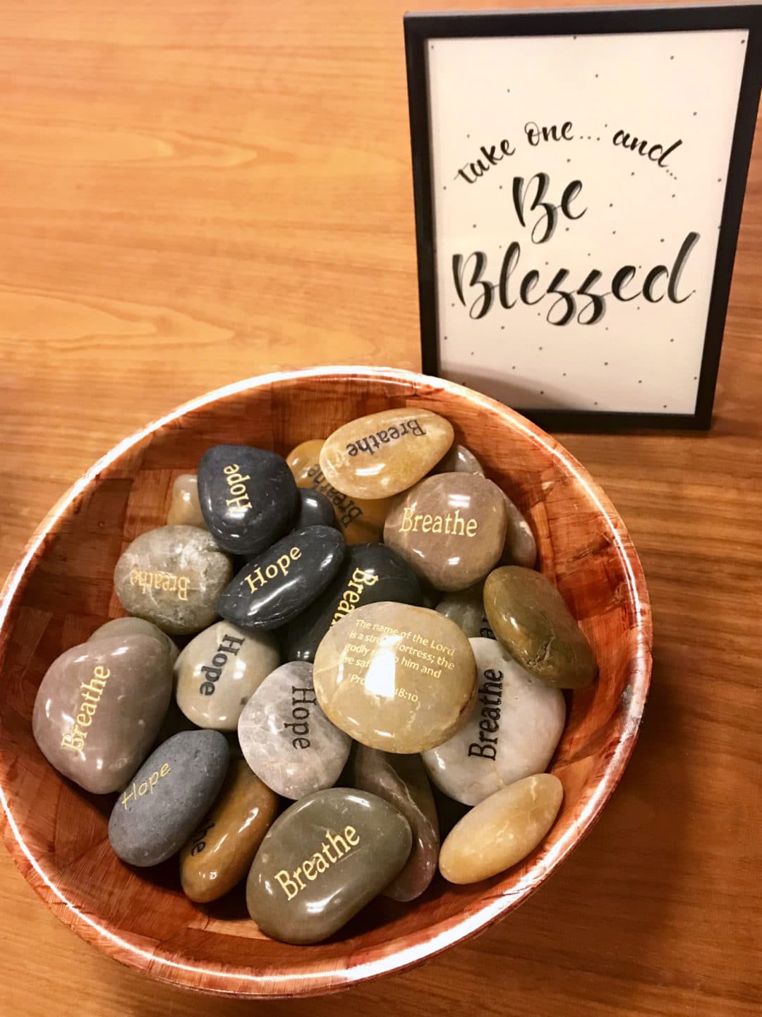 Polished rocks in a bowl next to a Be Blessed sign