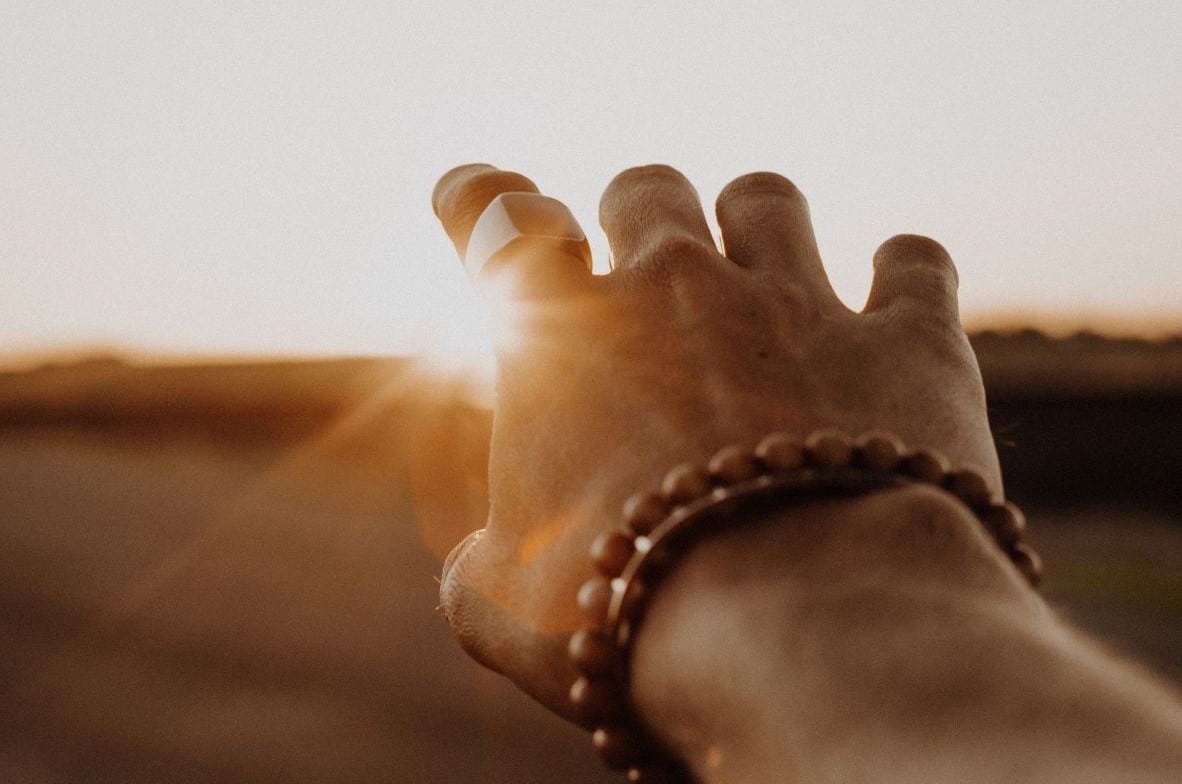 Close up of a hand reaching for the sunrise.