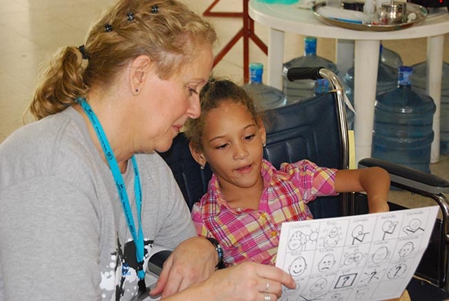 a volunteer teaching a child how to use a communication board