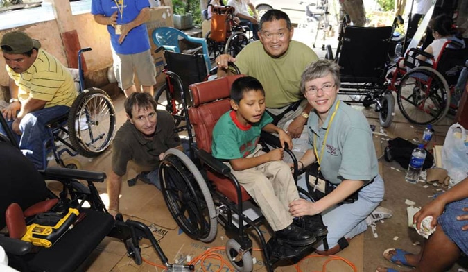 el salvador wheels for the world outreach ken tada and veronica hache at fitting a young boy with a new wheelchair