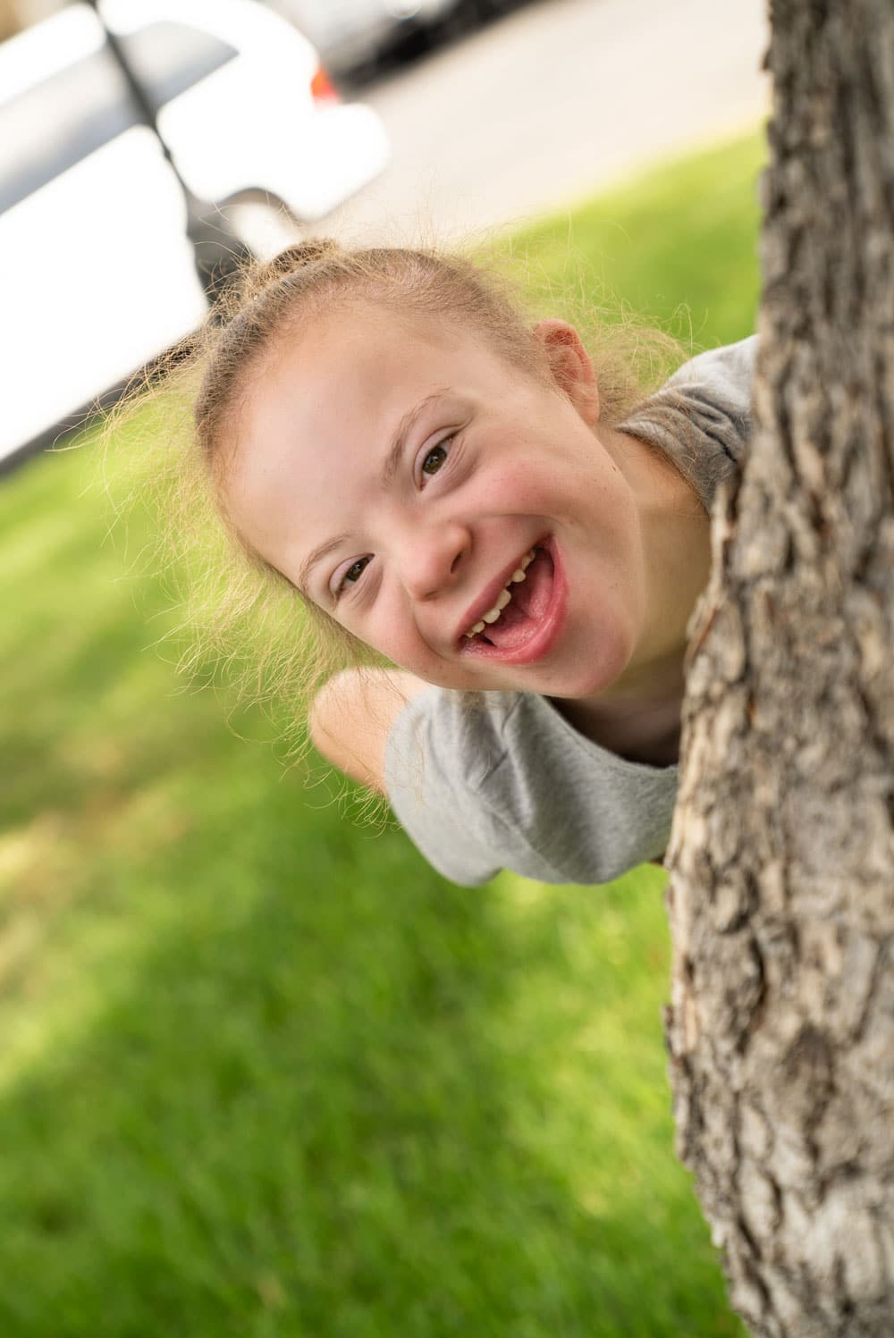 Sarah looking out from behind a tree.