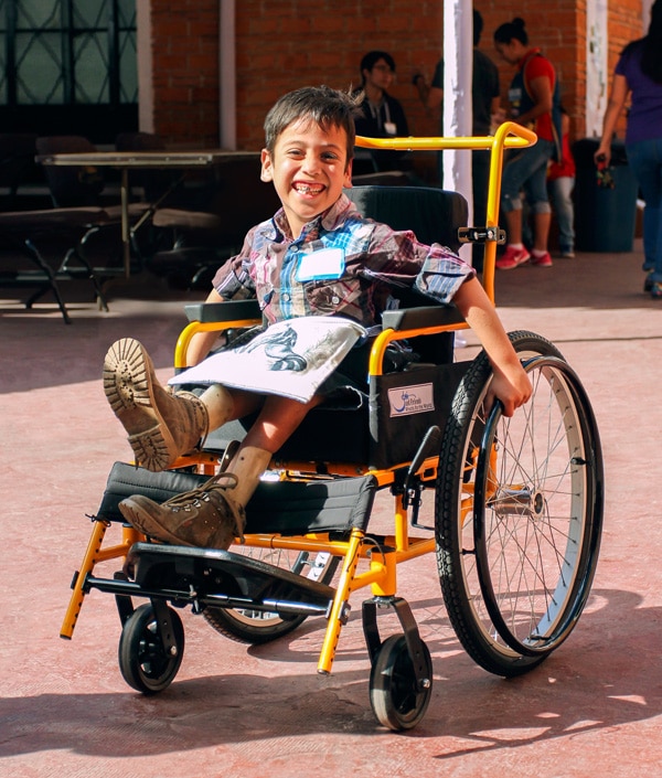 Boy receiving his firs pediatric wheelchair from Joni ad Friends Wheels for the World