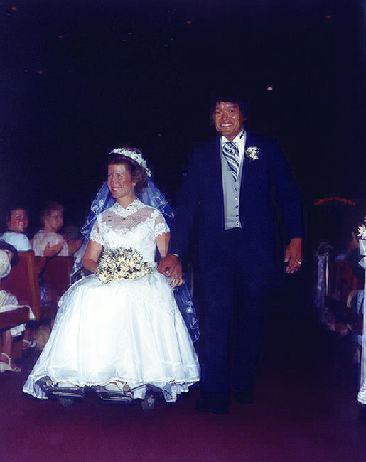 Joni in her wheelchair and Ken beside her as they make their way down the aisle.