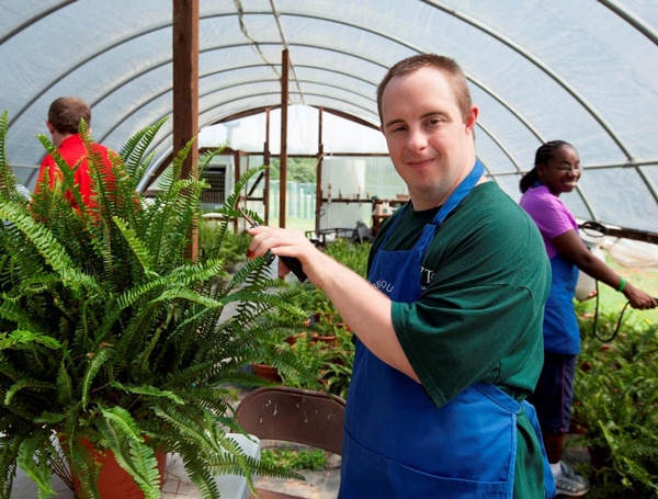 A man with Down Syndrome tends a garden A man with Down Syndrome tends a garden