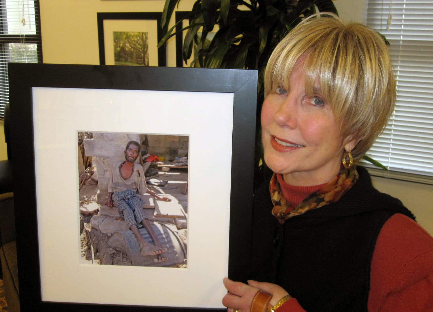 Joni Eareckson Tada holding a framed picture of an African man who is poverty stricken.