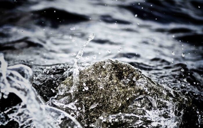 Stirred up water splashing around a rock.