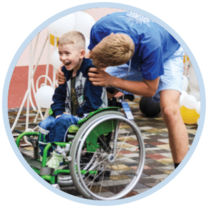 A boy in a wheelchair with a volunteer behind him.