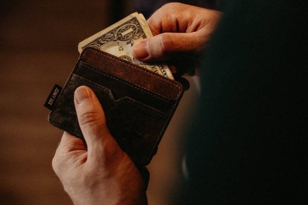 Close up of a man pulling cash out of his leather wallet.