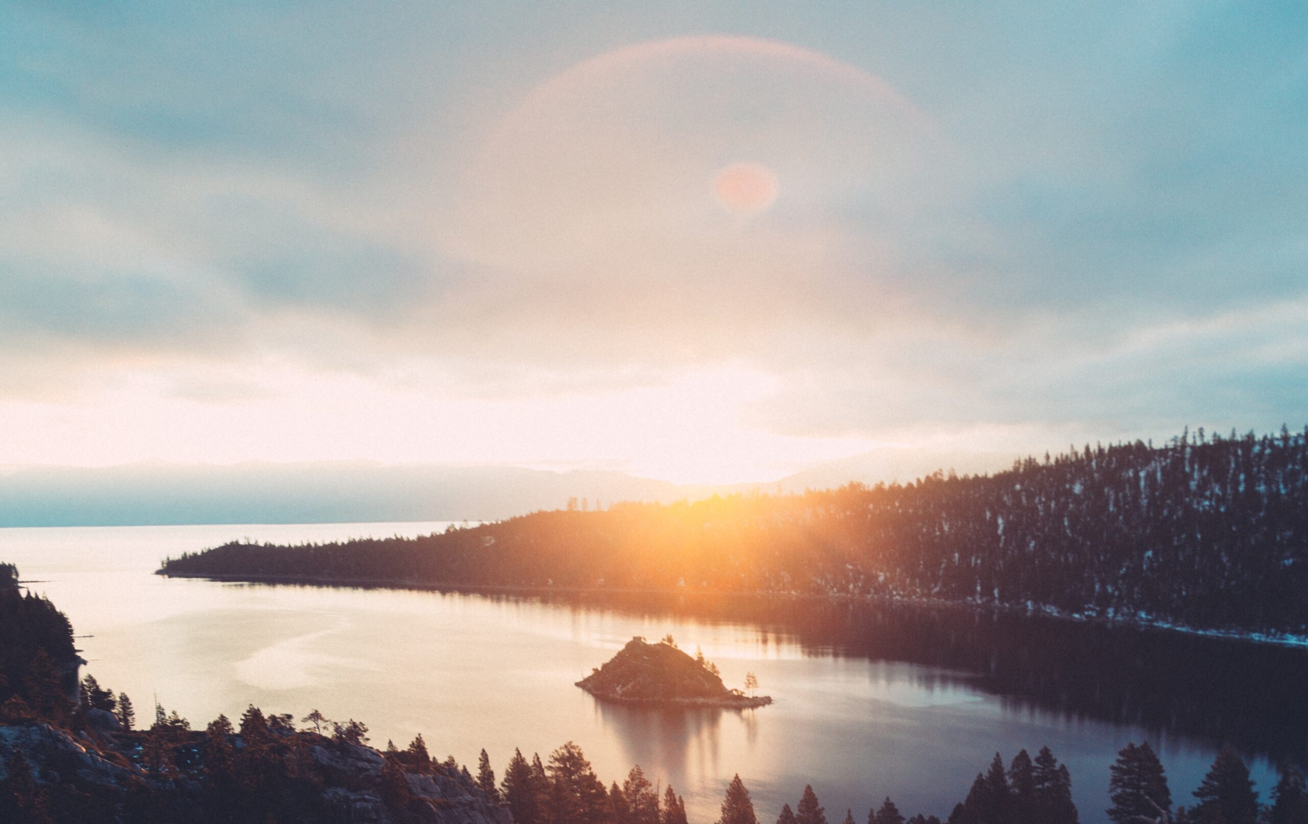 A beautiful view of the sun rising over a snowy, forested landscape.