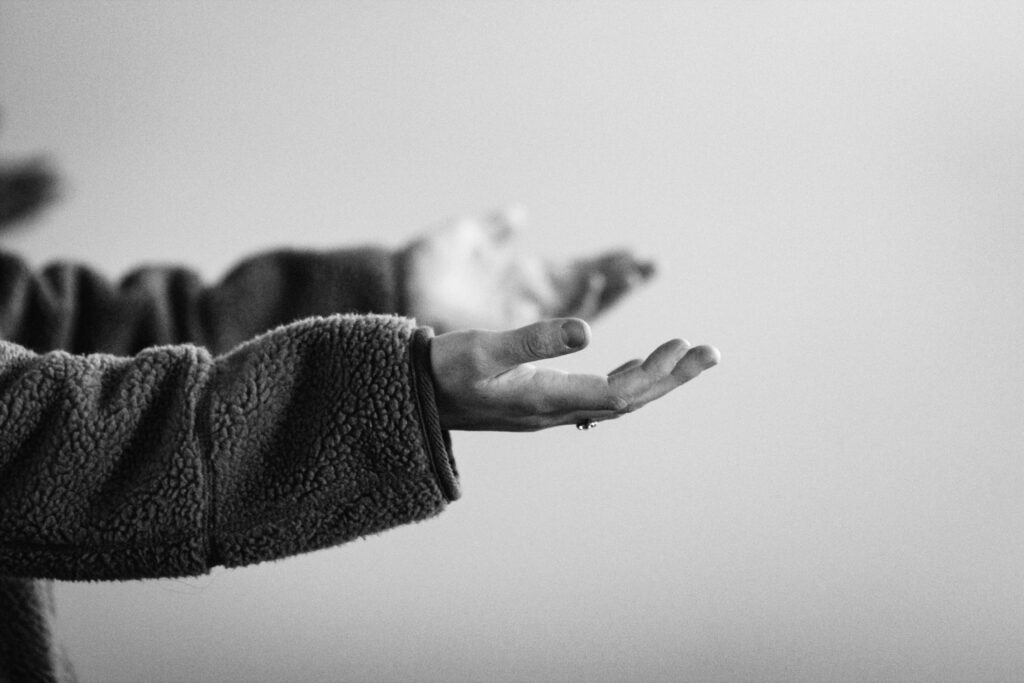 A black and white photograph showing a close-up of a person's outstretched, open hands facing upward