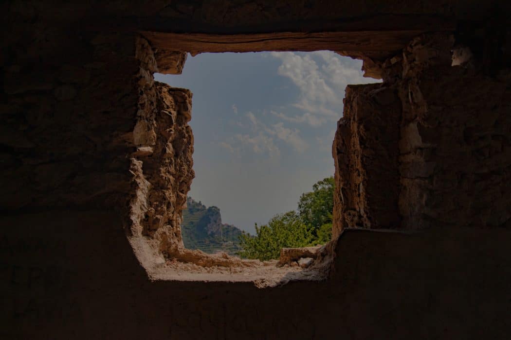 Close up on a desert valley in between the rocks with bushes and cliffs peaking out on the other end.