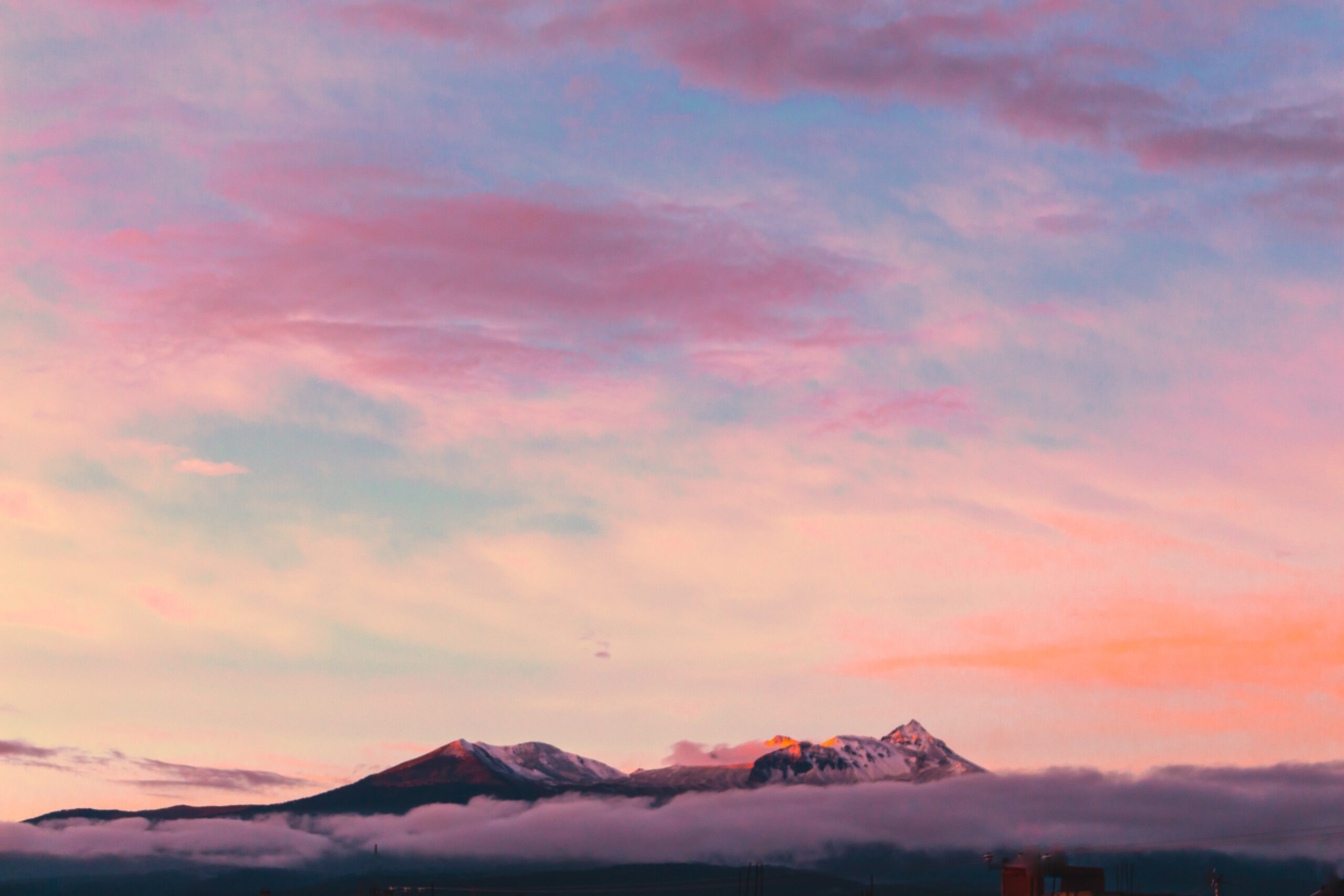 A sunset sky with snowy mountains on the horizon.