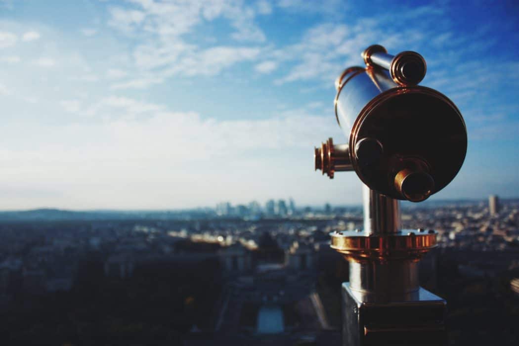 Close up of an old-timey telescope overlooking a major city.