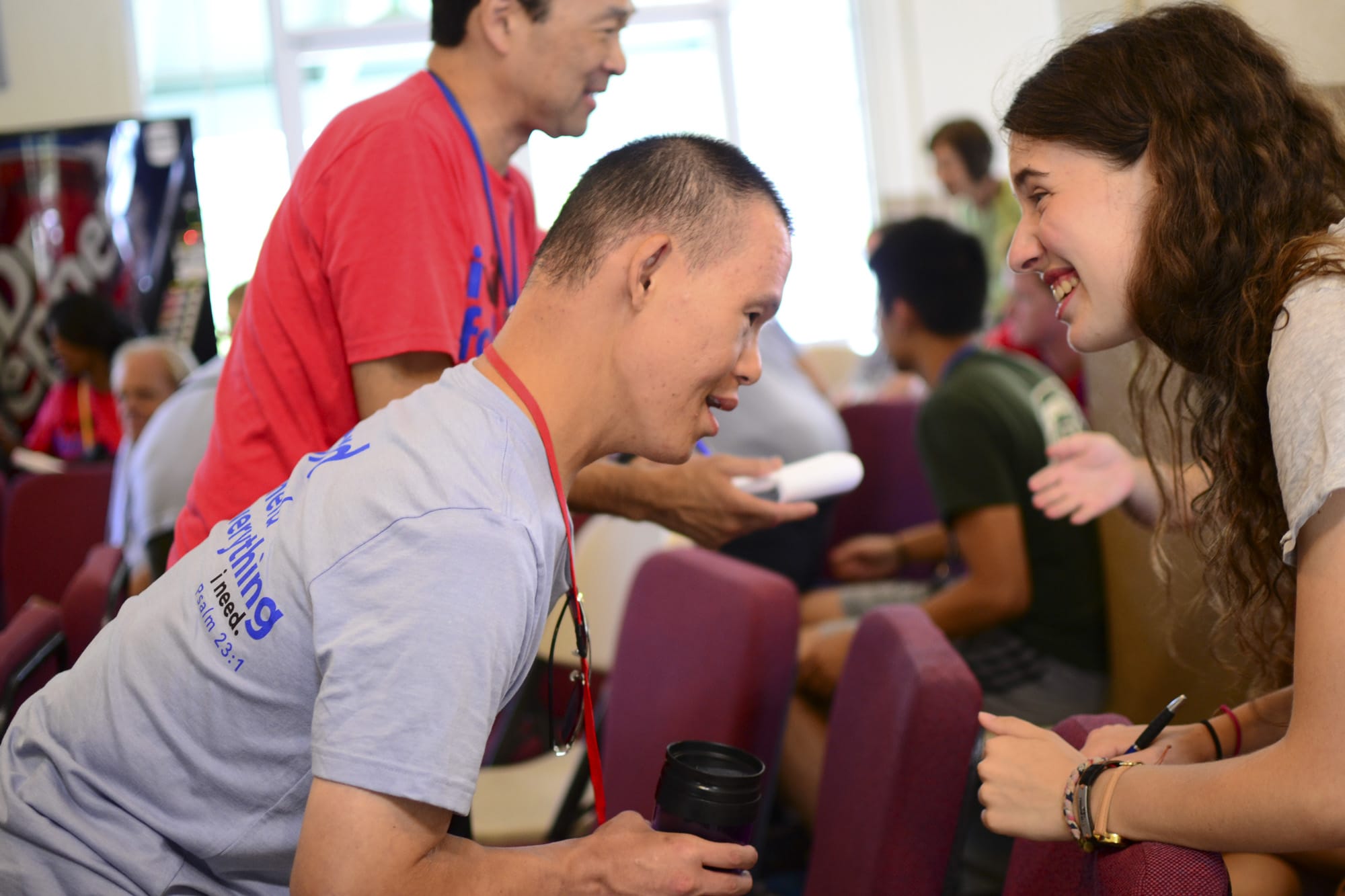 A man with special needs leaning over and smiling at a neurotypical woman across from him who is also smiling.