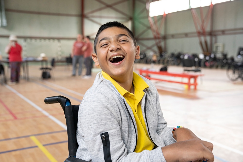 A boy smiles at the camera in his new wheelchair