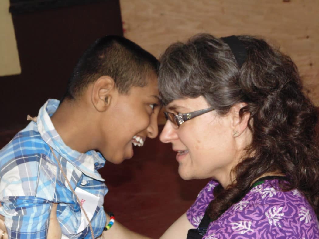 Close up of Kimi Archer and a young boy who appears to have a disability with their foreheads together as they look into each other's eyes and smile.