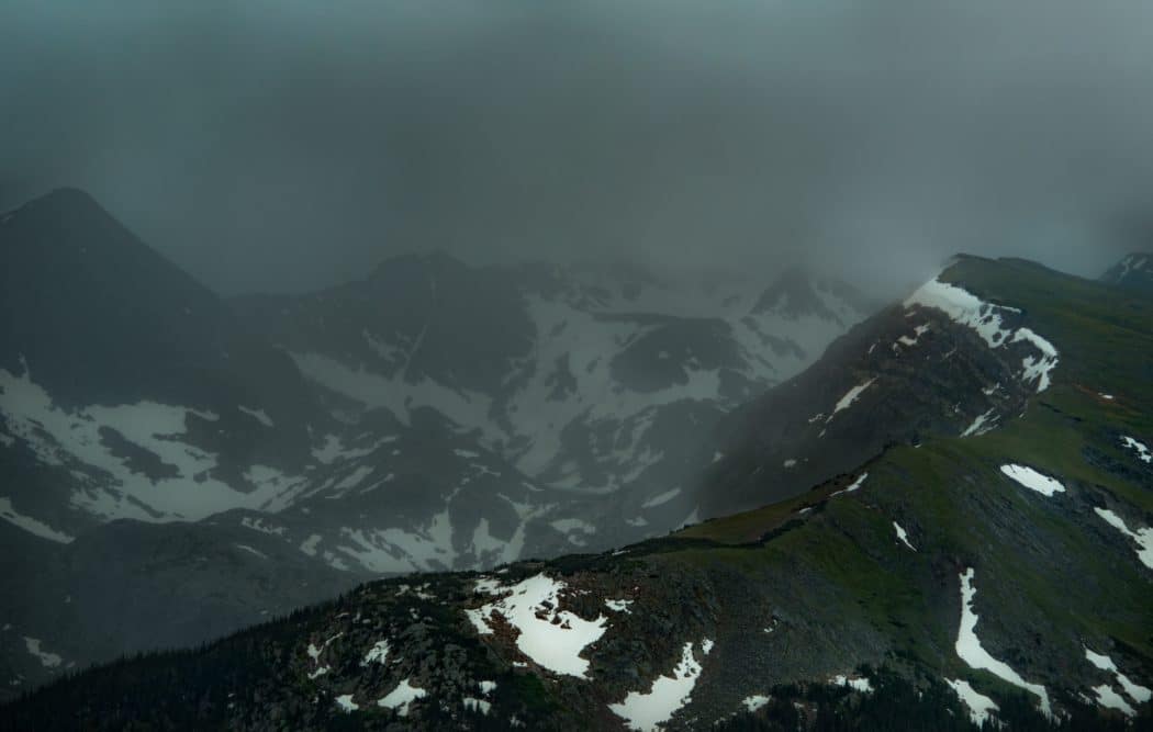 A snowy mountain range with thick mist settling over it.