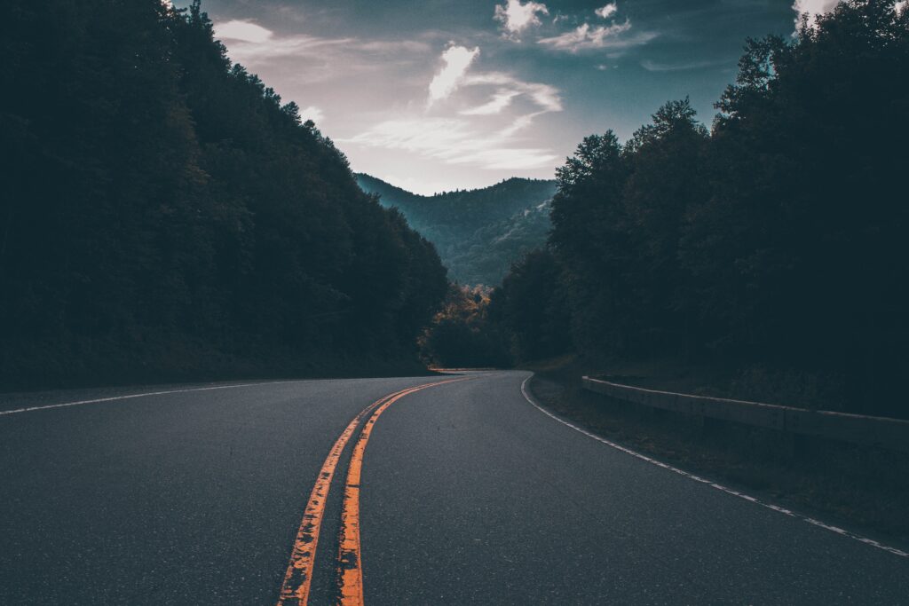 A winding road running through mountains with trees on them.