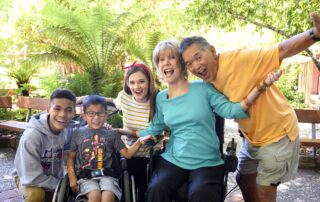 A group photo of Joni, Ken and three children, on who is seated in a wheelchair, the other two on either side of him.