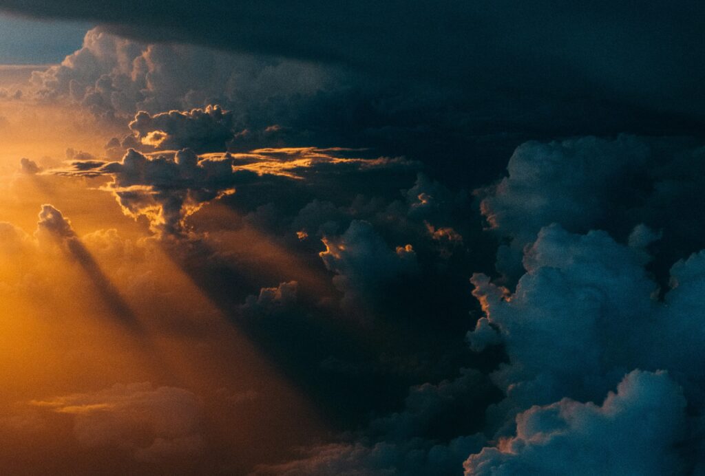 A picture of a cloud-darkened sky with a bright light shining in from beside the clouds.