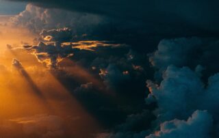 A picture of a cloud-darkened sky with a bright light shining in from beside the clouds.