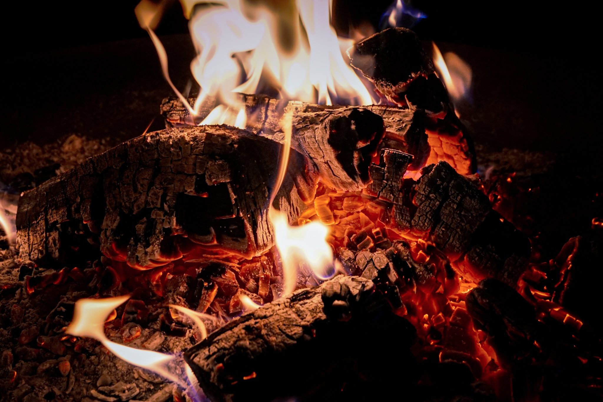 Close up of wooden logs burning in a fire pit.