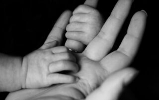 A close up of a hand and a baby grabbing its finger.