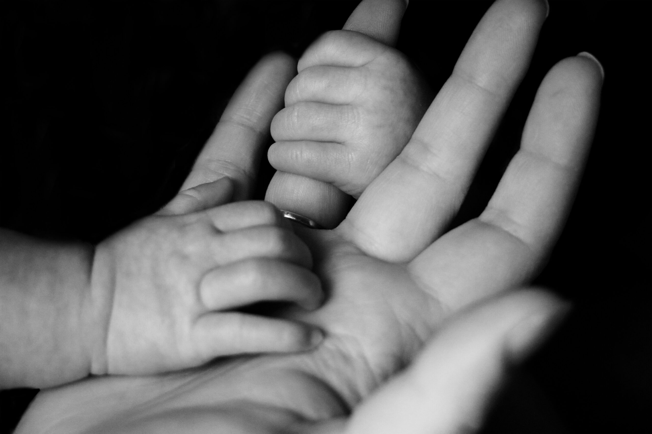 A close up of a hand and a baby grabbing its finger.