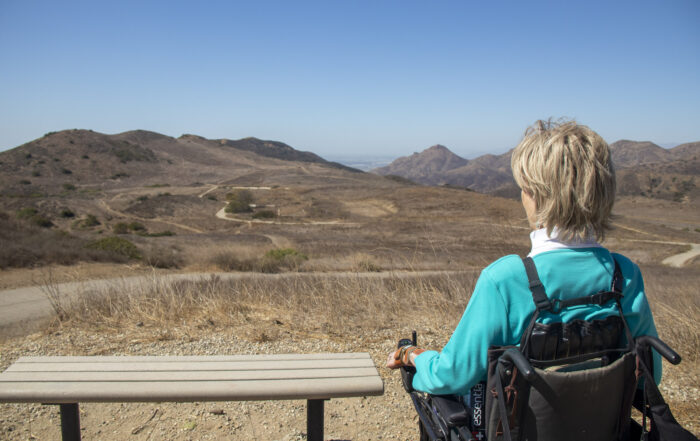 A picture of Joni staring out at mountains in front of her as she's seated in her wheelchair.