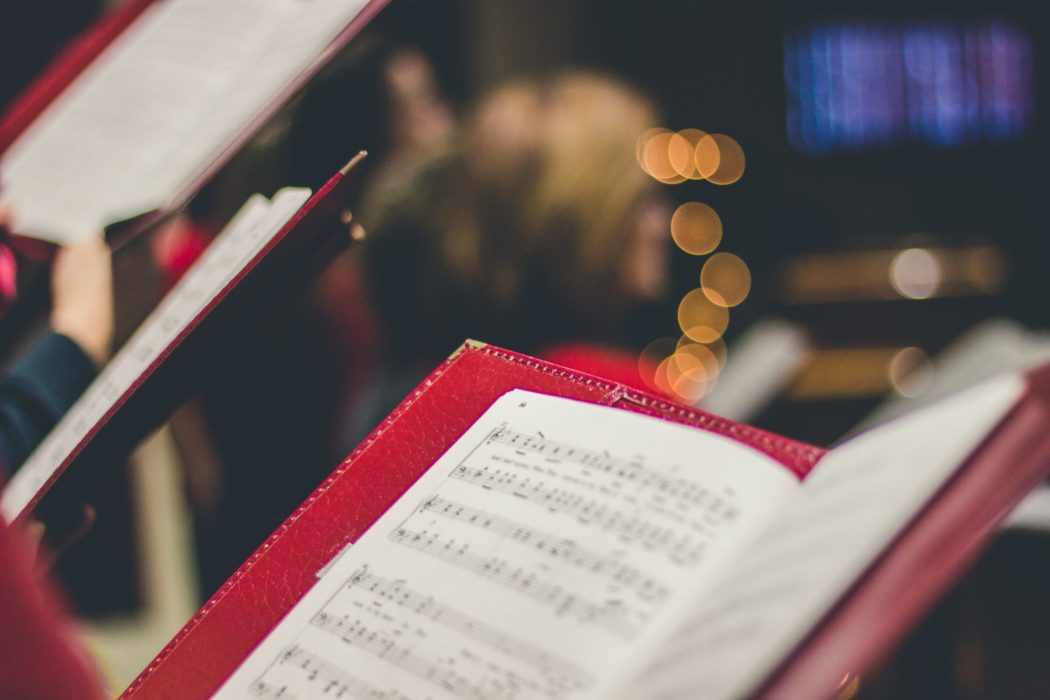 Close up of a book of music sheets held by a member of a choir.