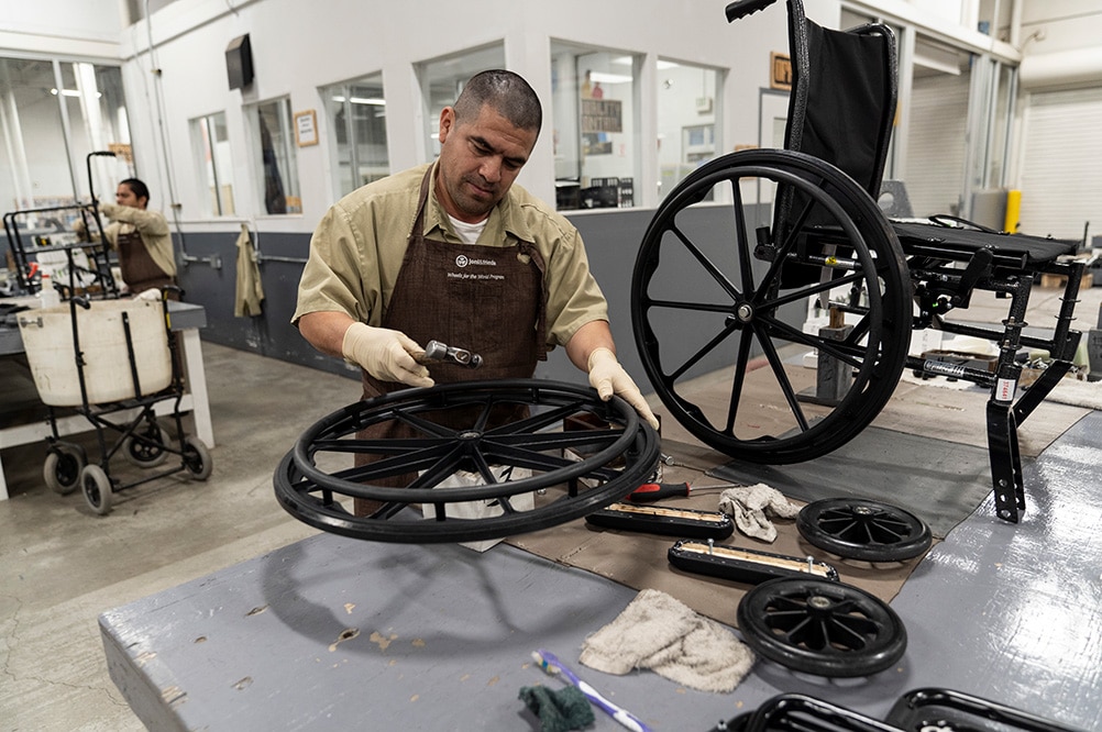 A man restoring the wheel of a wheelchair.