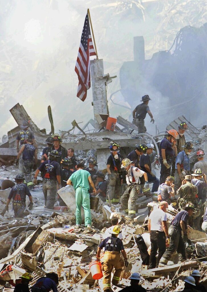 First responders climbing through the rubble caused by the 9/11 attacks to find people who may be buried beneath it. 