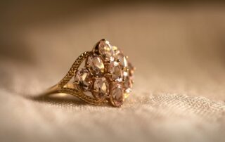 A close-up picture of a gold ring with gems or diamonds in it sitting on a piece of white linen.