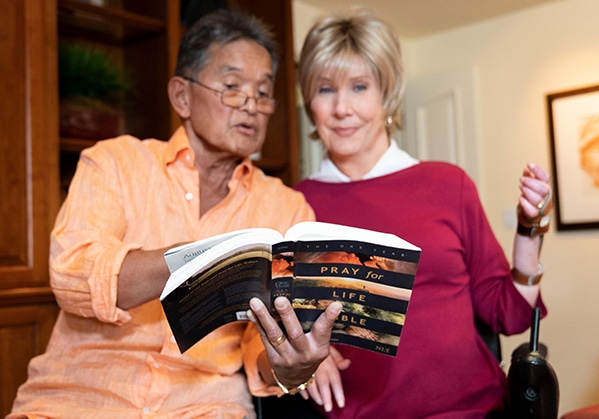 A picture of Joni and Ken smiling as they read the book "Pray for Life Bible."