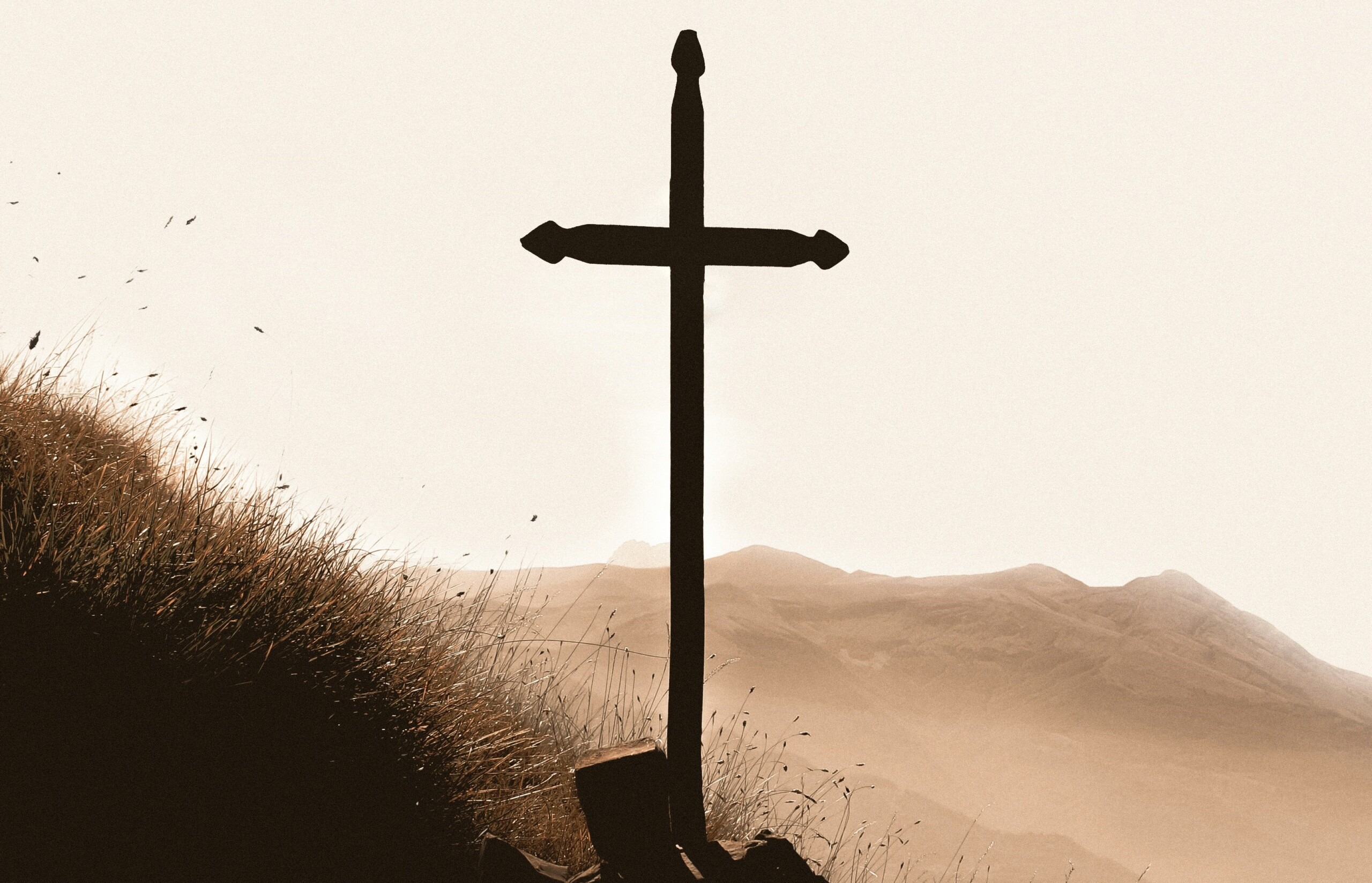 A close-up picture of a beautifully crafted wooden cross perched on a hill.