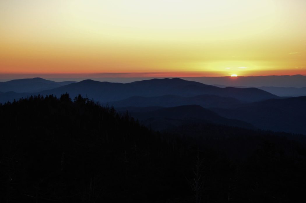 A view of a mountain range silhouetted against a vibrant sunset sky.