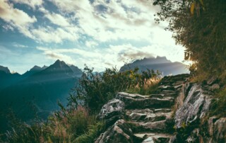 A picture of some natural steps along a cliffside with a mountain range in the background and a sky with clouds above.