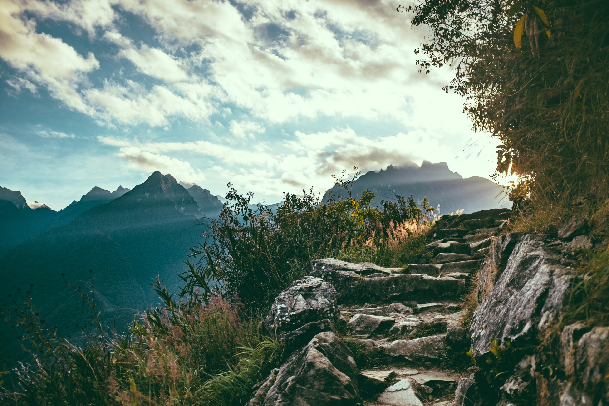 A picture of some natural steps along a cliffside with a mountain range in the background and a sky with clouds above.