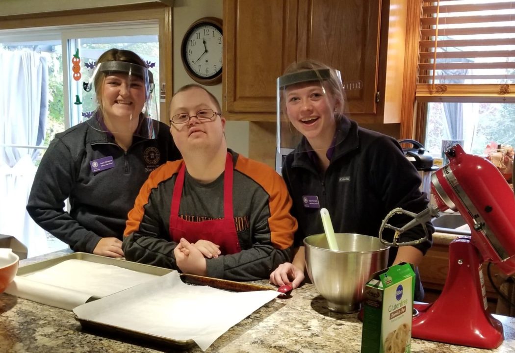 Two Joni and Friends volunteers serving in the respite program and baking in the kitchen with a young man with down syndrome.