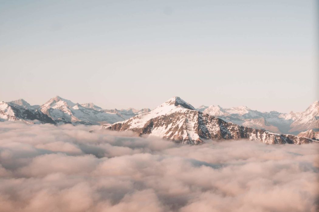 A snowy mountain peak surrounded by clouds.