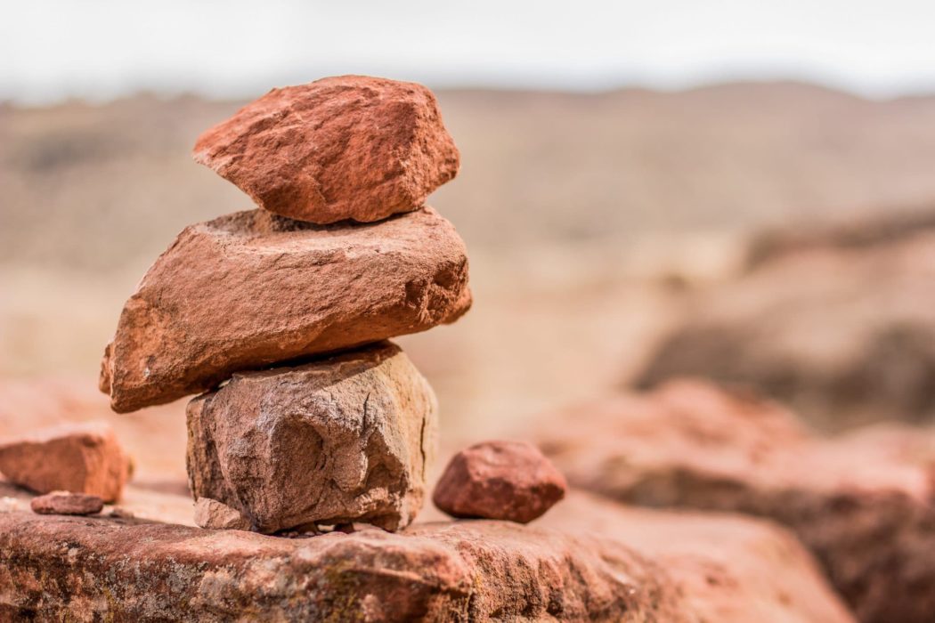 A stack of desert rocks, one on top of the other and a hazy desert landscape in the background.