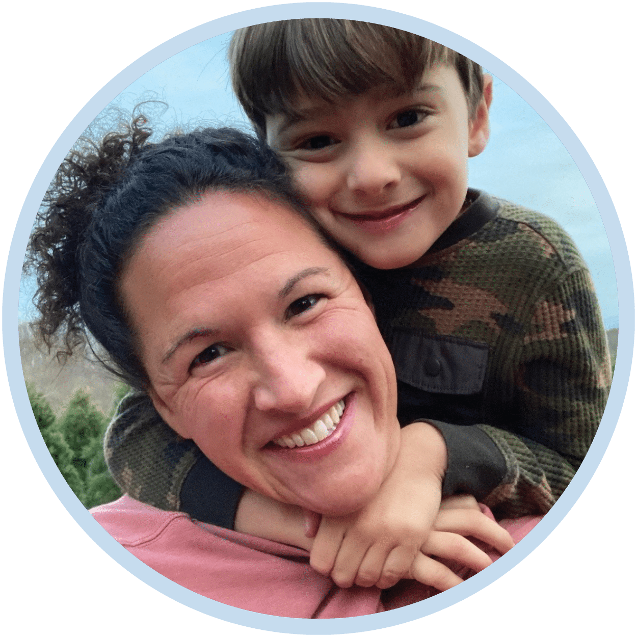 A mother with her son behind him hugging her.