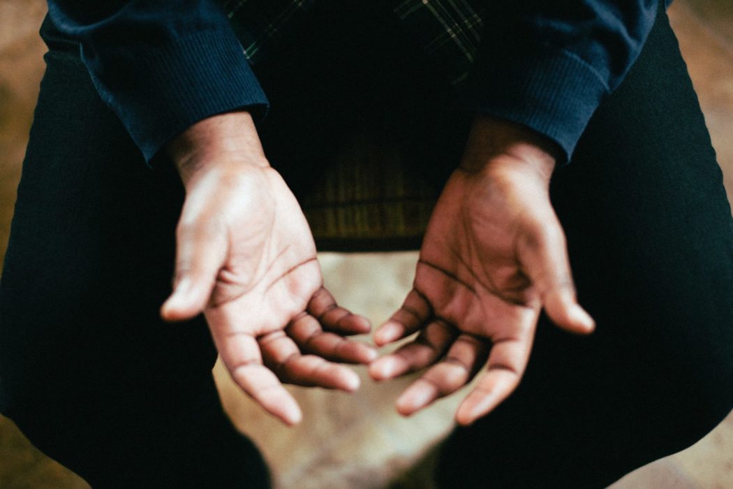 Close up of a man's hands open to prayer.