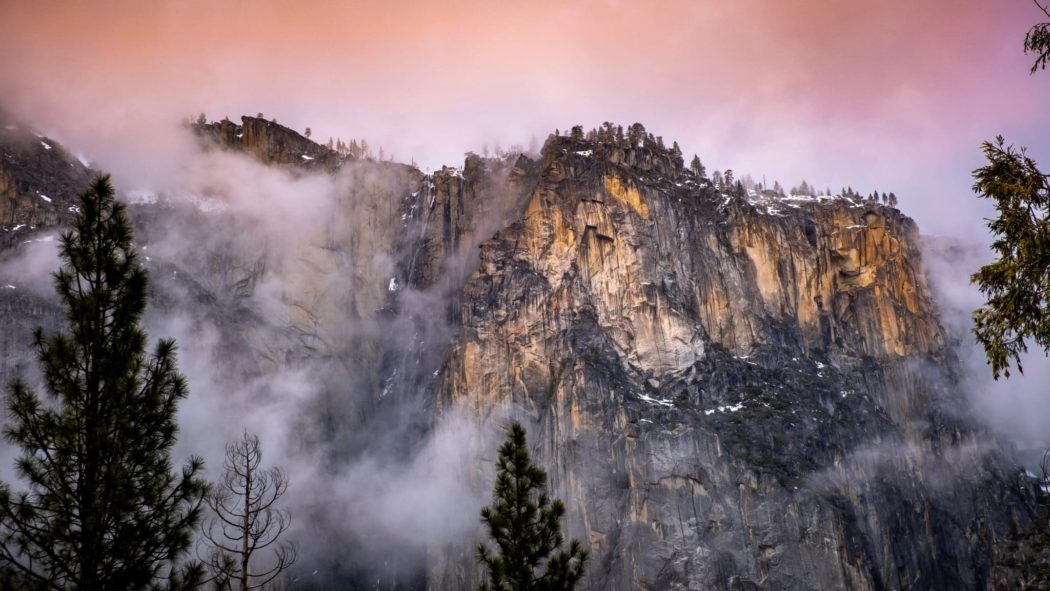 A rugged cliffside with fog surrounding it.