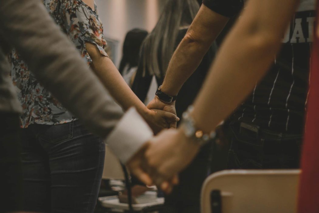 Close up of two couples, one in front of the other, holding hands.