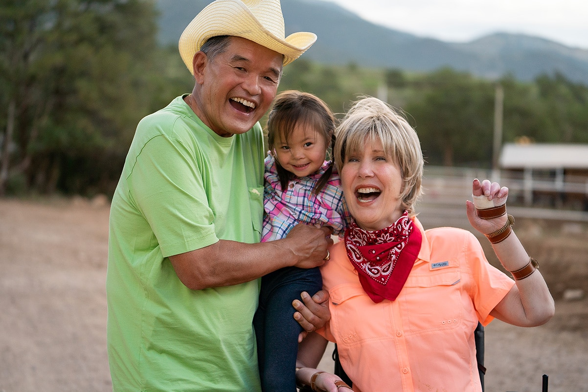 Joni and Ken holding a child as they pose for a photo