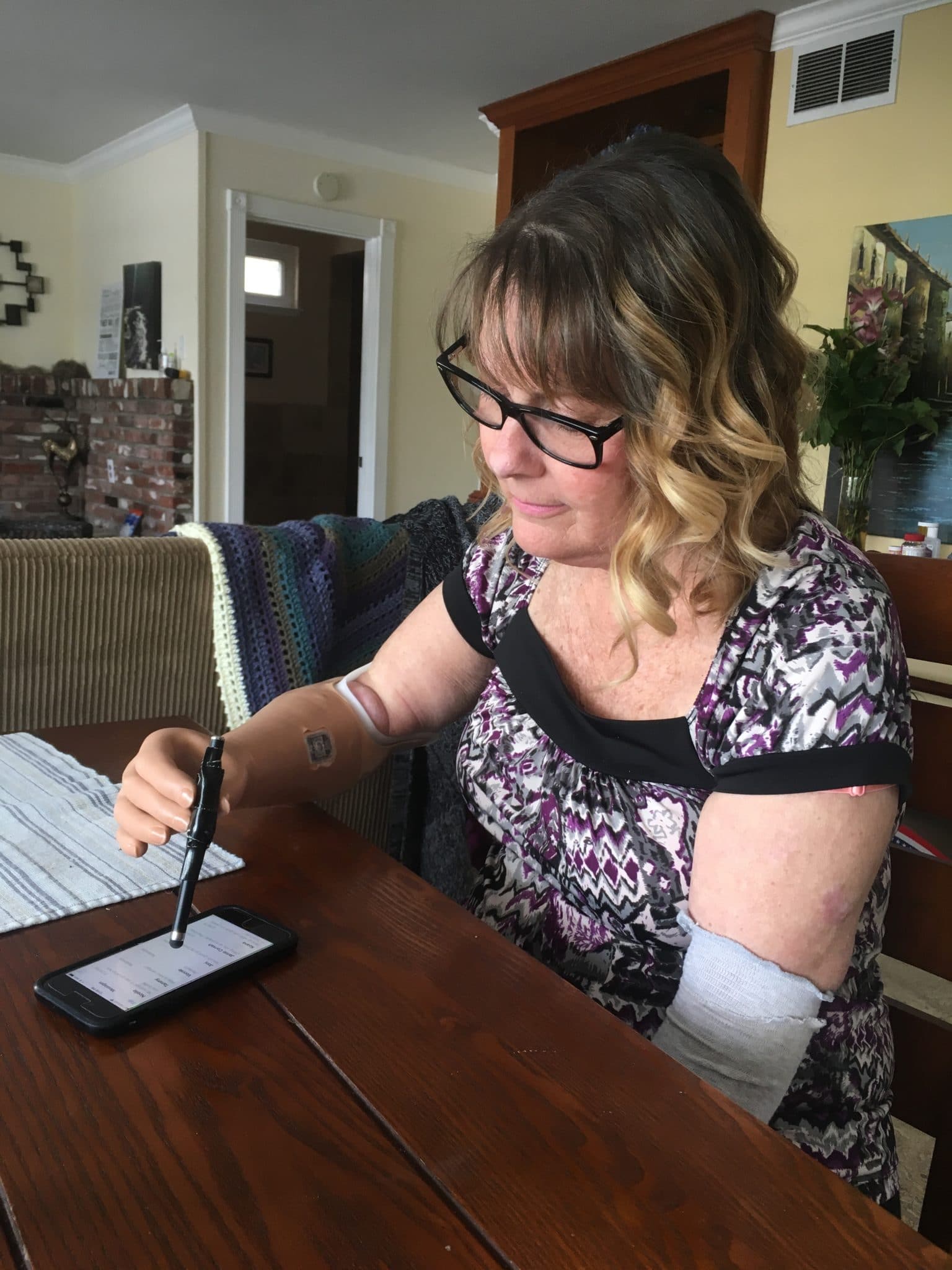 Vicki Zoradi using her phone with a touchscreen pen on a table indoors.
