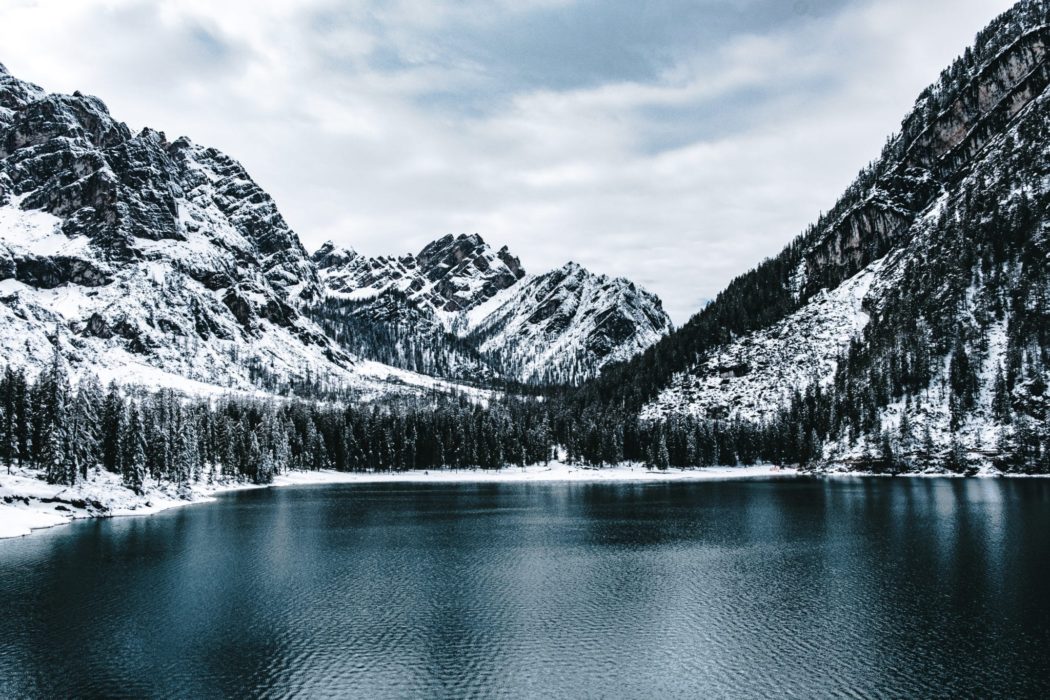 Snow-covered mountain rising above a lake on a bright daytime landscape.