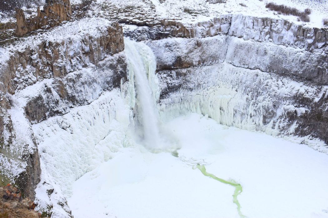 Palouse Falls, a 198-foot waterfall cascading into a rocky canyon, surrounded by rugged cliffs in Palouse Falls State Park. Formed by Ice Age floods.